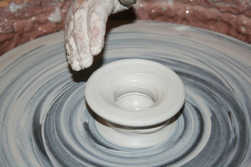 Artisan shapes clay on a spinning pottery wheel, creating a ceramic bowl.