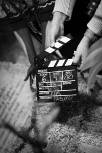 Black and white photo of hands holding a clapperboard on a film set, capturing cinematic action.